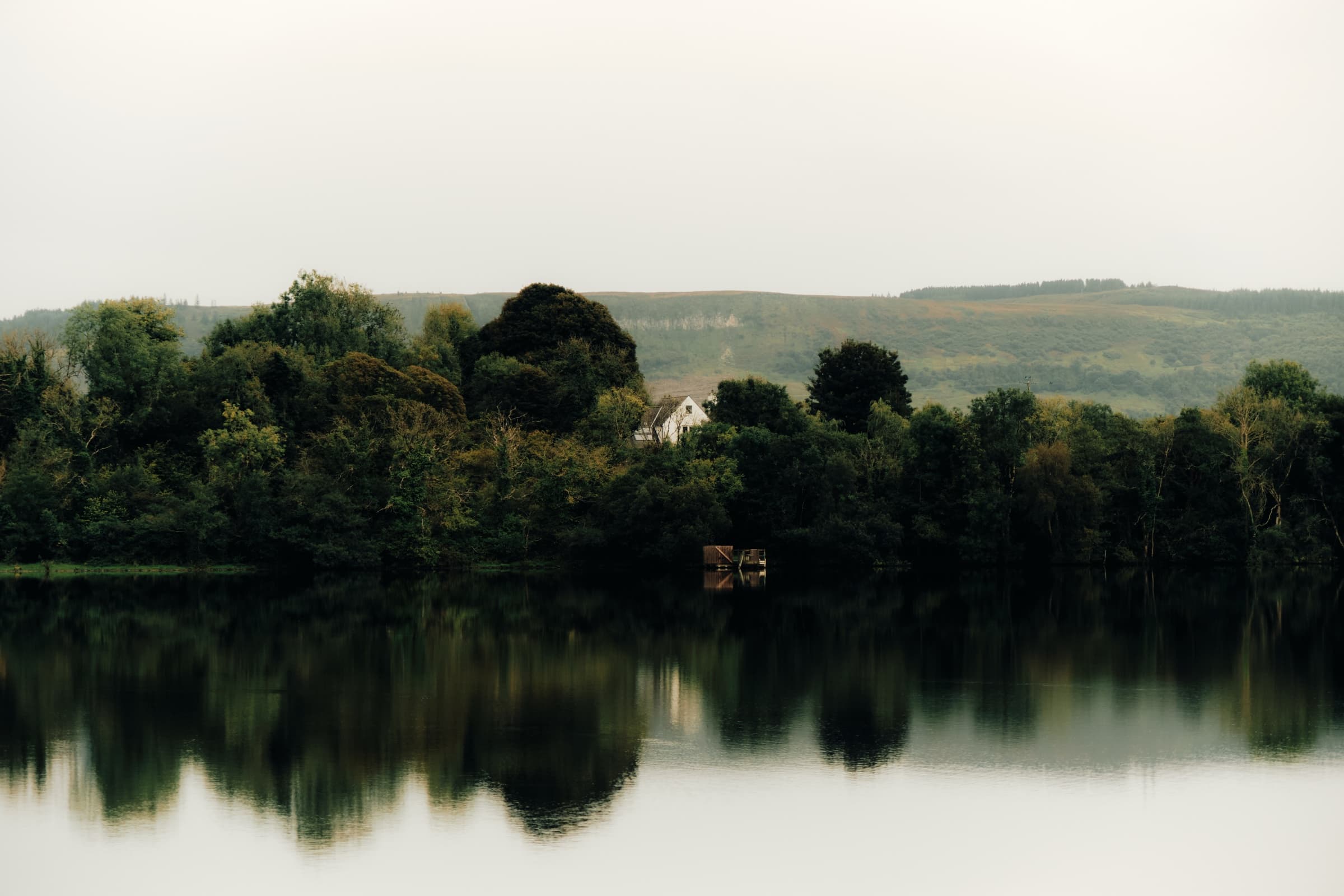 Fermanagh lake with a wooded shoreline and distant hills
